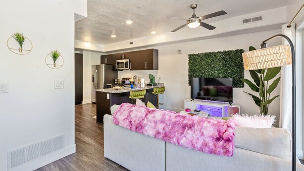 A modern living room with a sofa, a flat-screen TV, and a ceiling fan. - NEW-KING Bed Loft Apartment / Downtown/ Free Garage Parking/ GYM (Salt Lake City)