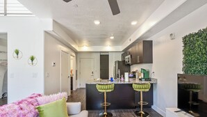 A modern kitchen with dark cabinets, a central island, and a green plant wall. - NEW-KING Bed Loft Apartment / Downtown/ Free Garage Parking/ GYM (Salt Lake City)