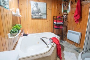 A wooden-paneled bathroom with a large bathtub, a shelf with towels, a Buddha statue, and a small plant. - Estate for 27 people with SPA and Festive BARN (Sainte-Ursule)