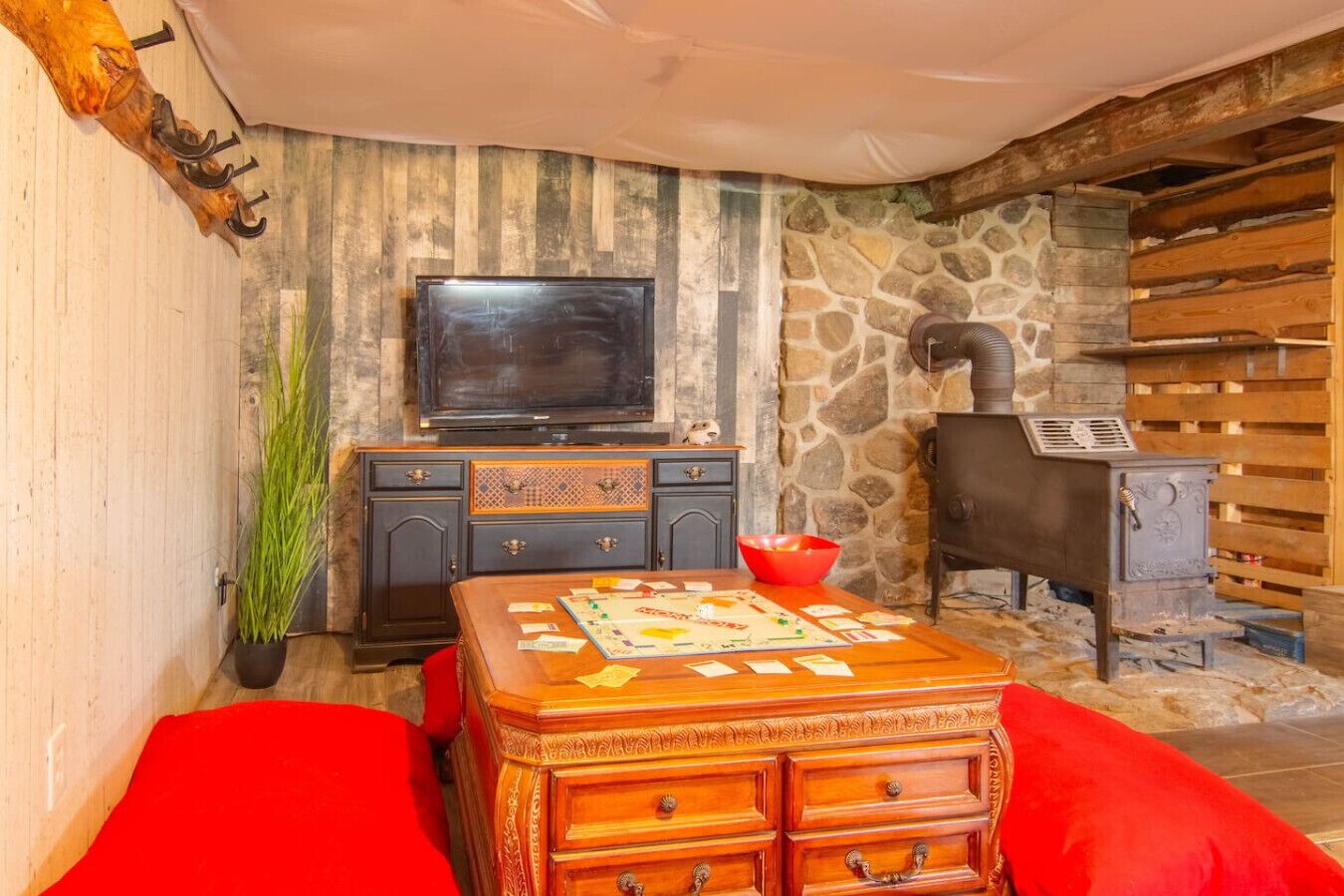 Una sala de estar acogedora con televisor, chimenea, aparador de madera y sofá rojo.
