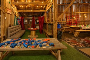 Ein rustikales Holzinterieur mit einer Couch, einem Tisch mit Bastelsachen und einer roten Leiter.