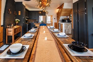 A long dining table set for multiple people with candles, surrounded by dark wooden cabinets and a stone wall. - Estate for 27 people with SPA and Festive BARN (Sainte-Ursule)