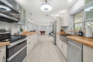 Een moderne keuken met roestvrijstalen apparatuur, houten aanrechtbladen en een centraal eiland.