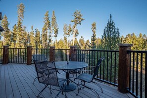 Eine Terrasse mit einem runden Tisch und Stühlen, umgeben von einer Holzrelung.