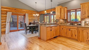 A log cabin-style kitchen with wooden cabinets, a dining area, and a view through a glass door. - Tabernash 5BR Retreat | Hot Tub, Golf & Skiing (Winter Park)