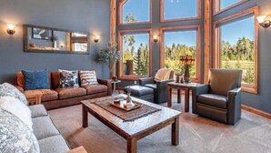 A spacious living room with large windows, a fireplace, and a cozy seating area. - Tabernash 5BR Retreat | Hot Tub, Golf & Skiing (Winter Park)