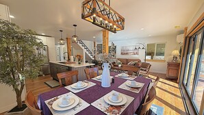 Un comedor con una mesa dispuesta para cuatro personas, una escalera y vistas al exterior.