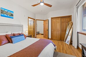 Ein Schlafzimmer mit Bett, Holzschrank und Deckenventilator.