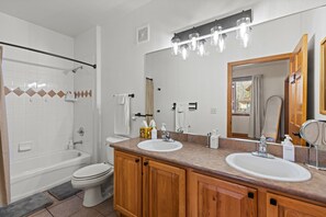 Ein Badezimmer mit Badewanne, Toilette und einem Doppelwaschtisch.