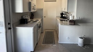 A compact kitchen with white cabinets, a stove, a microwave, and a sink. - Southwest-Chic 1BR Casita, Private Yard + Driveway, Northern Phoenix Getaway (Glendale)