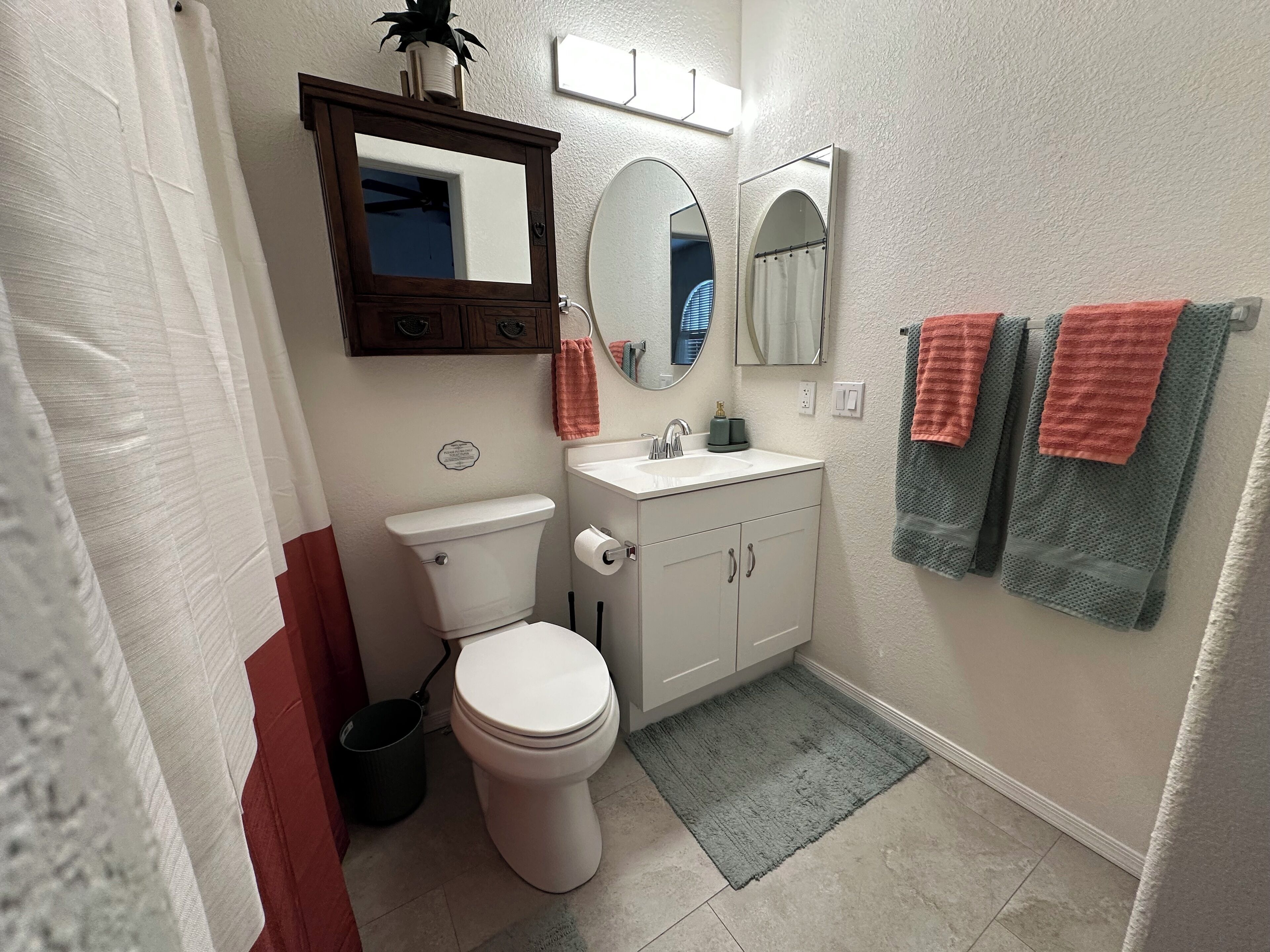 A bathroom with a toilet, sink, mirrors, and towels.