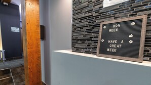 Et receptionsområde med et skilt, der siger "BON WEEK HAVE A GREAT WEEK" mod en sort baggrund med hvid tekst og dekorative ikoner.
