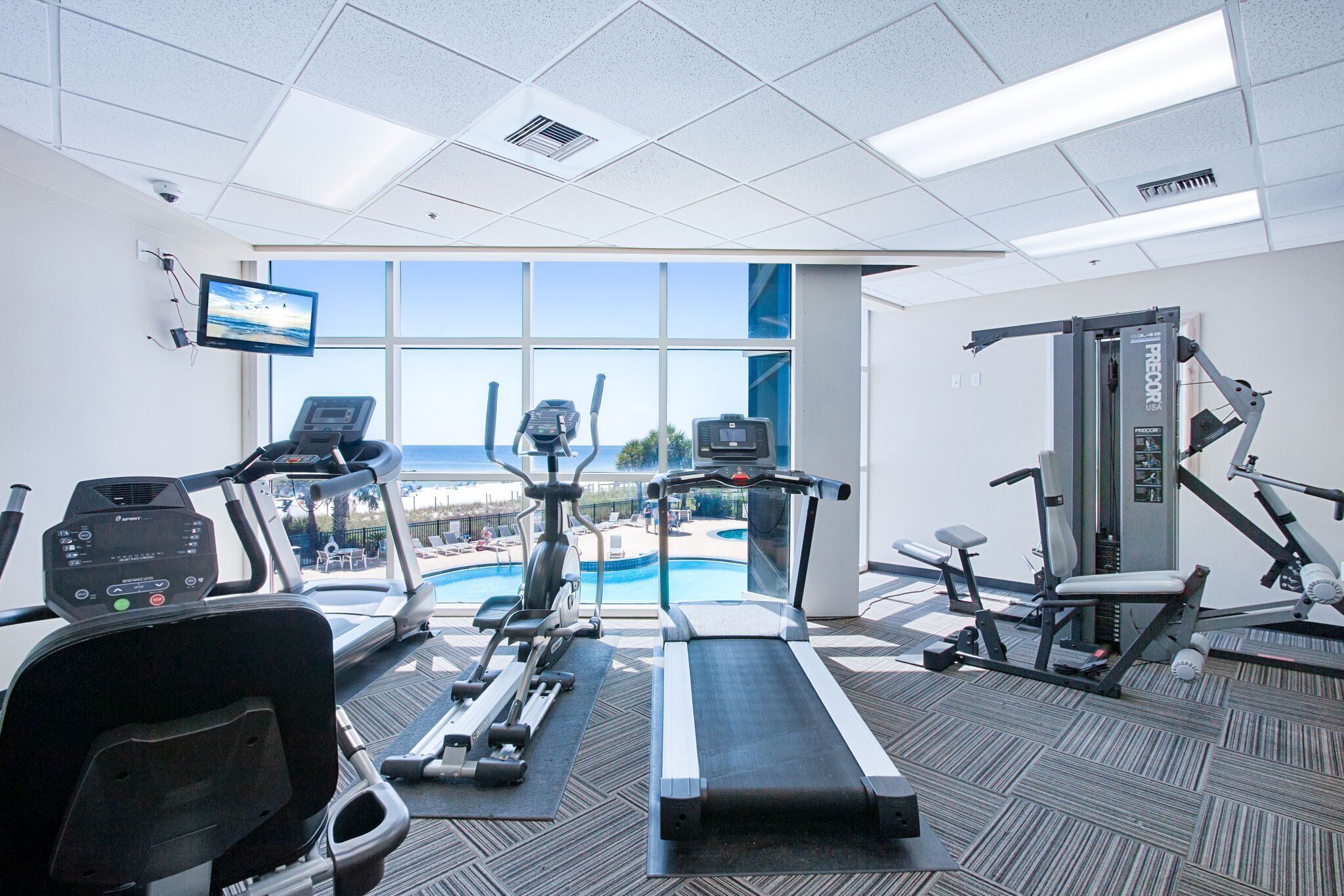 Une salle de sport équipée de tapis de course, de vélos elliptiques et de matériel de musculation.