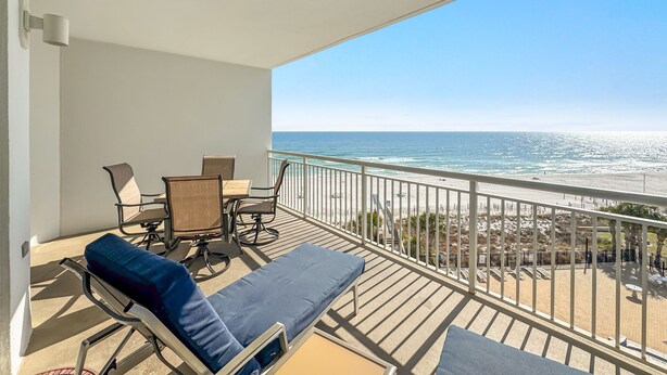 A balcony with a view of the ocean, a table with chairs, and a lounge chair. - Palacio 403 | Beachfront | My Beach Getaways (Pensacola)