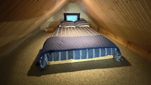 Ein gemütliches Schlafzimmer im Dachgeschoss mit einem Bett, einem Fernseher und einem kleinen Nachttisch.