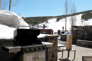 An outdoor grill area with a stone structure, a chimney, and a view of a snowy mountain landscape. - Grand Colorado on Peak 8 Suite Ski in/ Ski out in Bldg. 3 (Breckenridge)