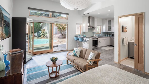Un grand salon comprenant un canapé, une table basse et donnant sur une piscine et un jardin.
