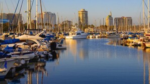 Un port de plaisance où sont amarrés différents types de bateaux, entouré d’immeubles.