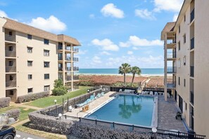 Ein Poolbereich mit Blick auf den Strand, umgeben von Apartmentgebäuden.