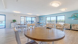 Una habitación amplia con una gran mesa redonda, sillas blancas y un juego de sofá estampado.