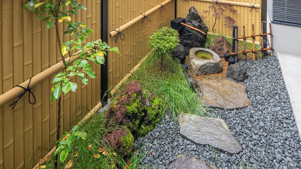 A bamboo fence, a small rock garden, and a building with a white exterior. - ORVIA YIG VILLA (Furano)