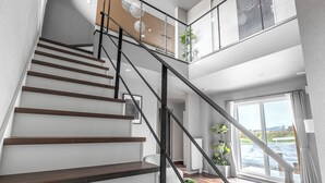 A modern staircase with wooden steps and metal railings, leading to a balcony with a view of a body of water. - ORVIA YIG VILLA (Furano)