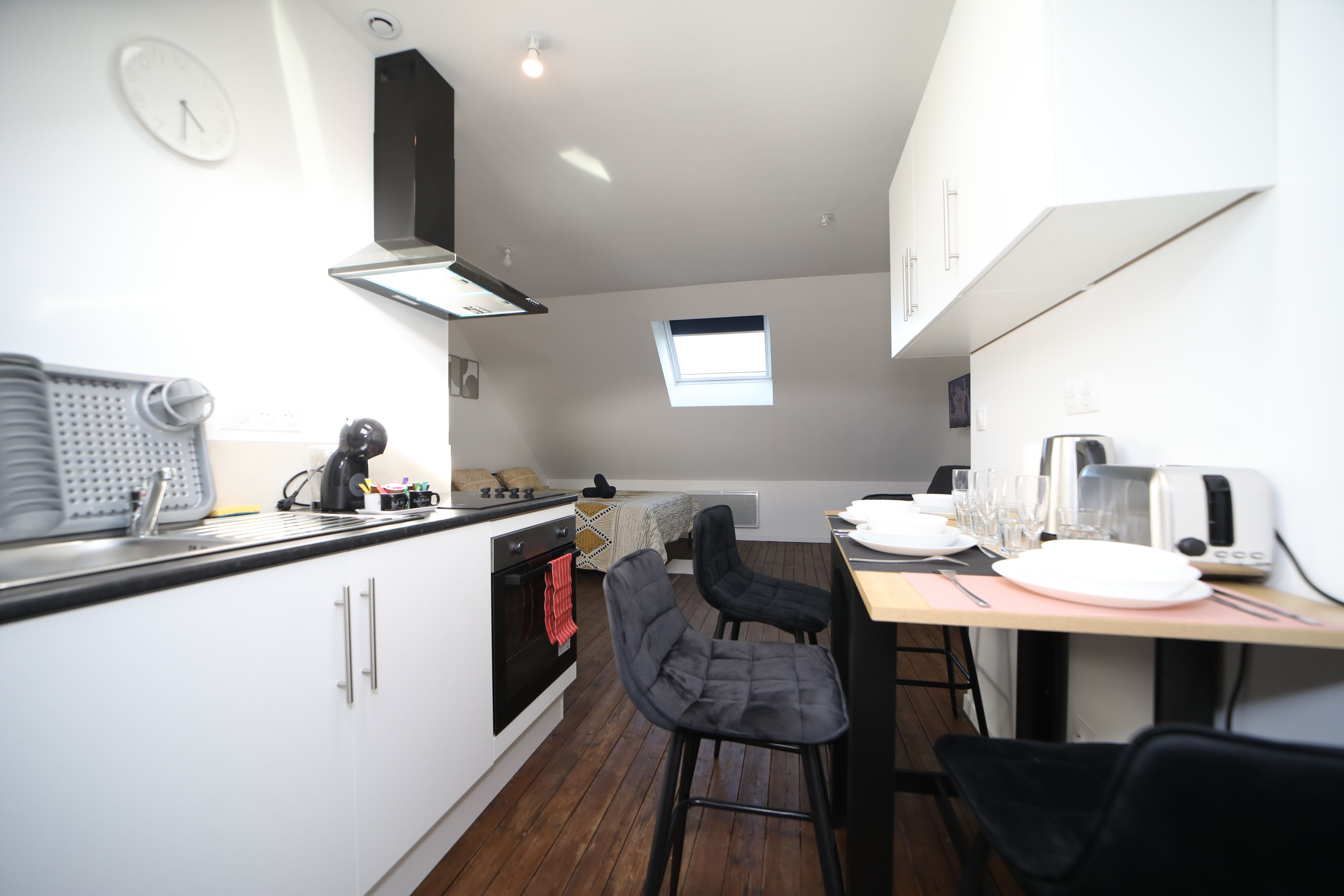 Una cucina moderna con mobili bianchi, un piano di lavoro nero e una finestra sopra il lavello.