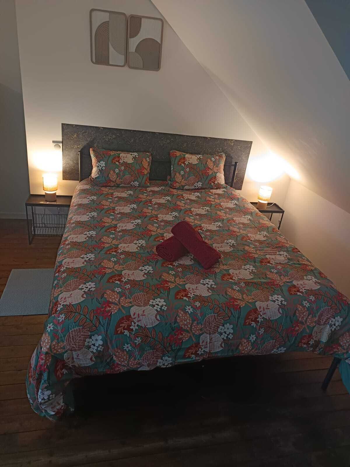 Un dormitorio con cubrecama floral, dos lámparas de noche, un cabecero y dos piezas de arte decorativo en la pared.