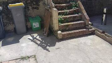 A staircase with a metal handrail, a trash bin, and a green recycling bin.