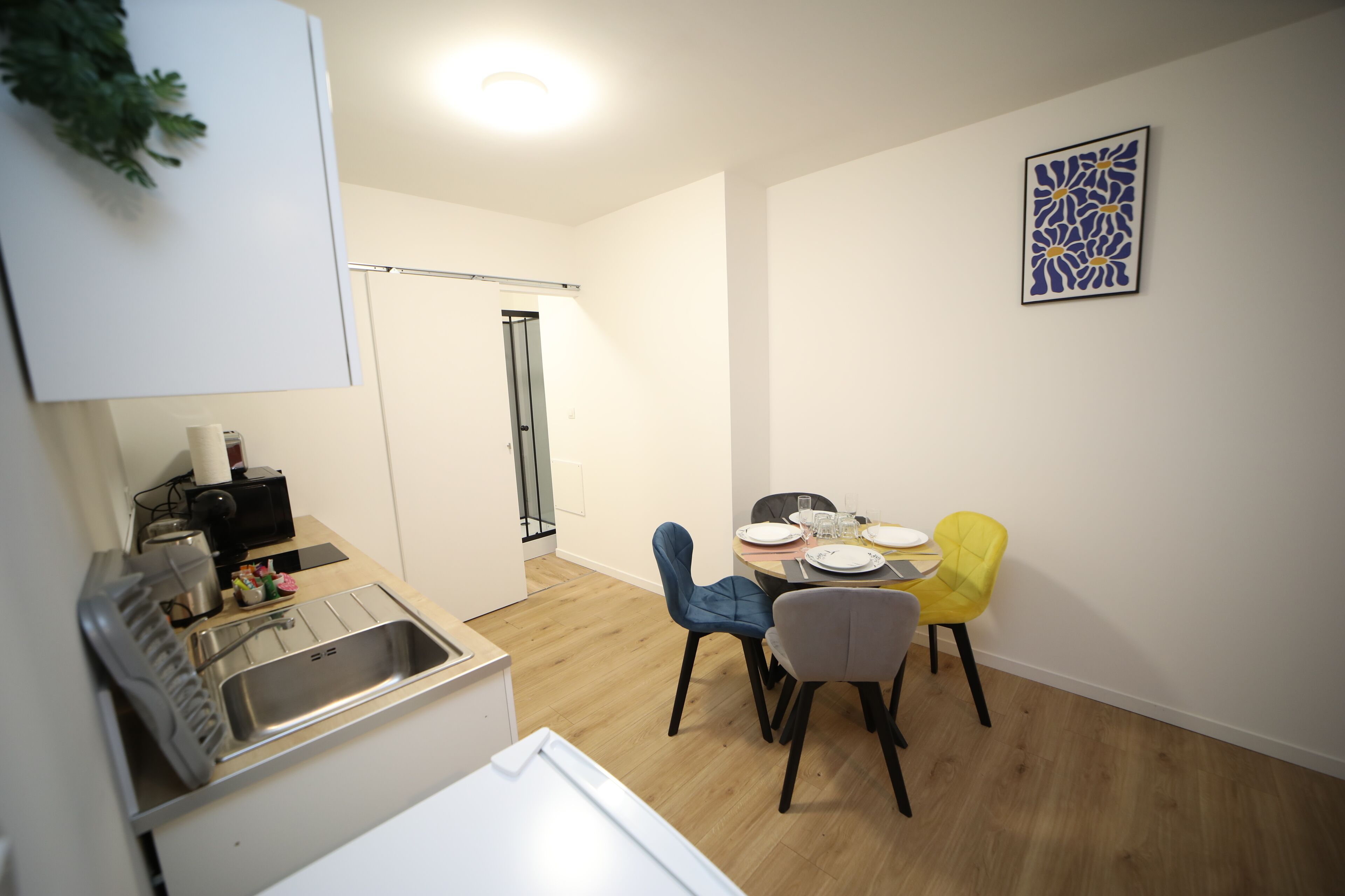 A compact kitchen with a sink, a small countertop, and a dining area with two chairs and a table.