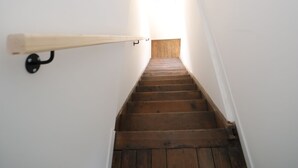 A wooden staircase with white walls and a wooden handrail. - Eden (Cambrai)