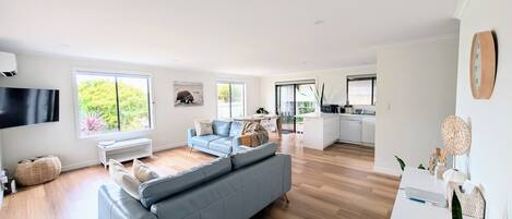 A modern living space with a sofa, a flat-screen TV, and a dining area.