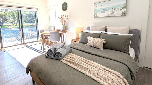 A modern bedroom with a large bed, a desk, and a view through the glass doors. - The Duck House: Modern, Rural, 3 min drive to town (Kingscote)