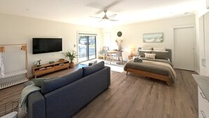 A modern living room with a sofa, TV, and dining area. - The Duck House: Modern, Rural, 3 min drive to town (Kingscote)