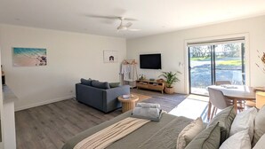 A modern bedroom with a bed, a sofa, a TV, and a dining area with a view. - The Duck House: Modern, Rural, 3 min drive to town (Kingscote)