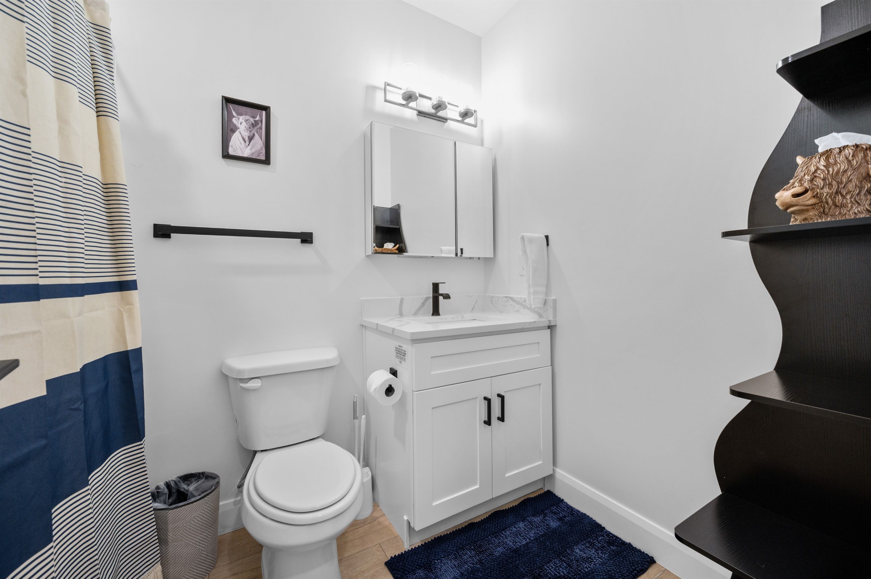 A bathroom with a toilet, sink, mirror, and towel rack.