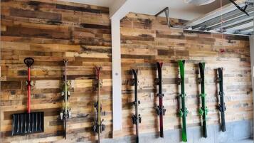 A ski rack with skis and a shovel mounted on a wooden wall.