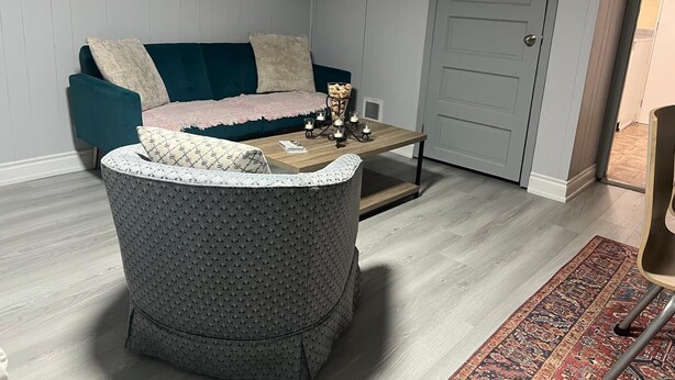 Una sala de estar acogedora con un sofá color turquesa, un sillón estampado, una mesa de centro y una alfombra con diseño.