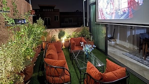 An outdoor patio with a sofa set, a glass table, and potted plants. - Rooftop & Cinema - Luxury in the heart of Marrakech (Marrakesh)