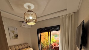 A bedroom with a large bed, a television mounted on the wall, and a view of the outdoor patio. - Rooftop & Cinema - Luxury in the heart of Marrakech (Marrakesh)