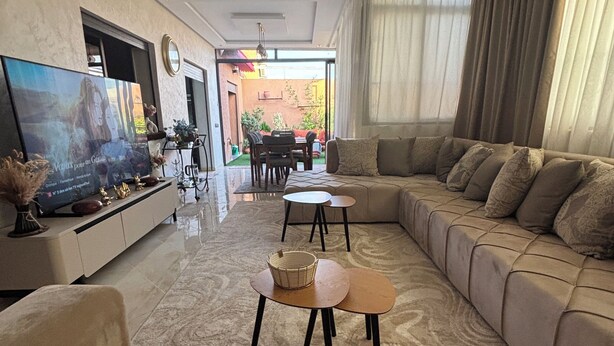 A modern living room with a large sectional sofa, a flat-screen TV, and a dining area visible through an open door. - Rooftop & Cinema - Luxury in the heart of Marrakech (Marrakesh)