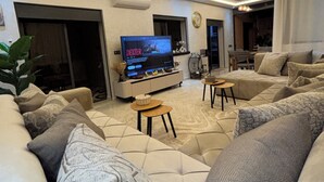 A modern living room with a large TV, comfortable seating, and a decorative ceiling light. - Rooftop & Cinema - Luxury in the heart of Marrakech (Marrakesh)