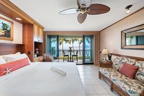 A hotel room with a large bed, a sofa, a ceiling fan, a balcony with a view of the ocean, and a dining area with a table and chairs. - Oceanfront Studio w Lanai, AC & Sunset Views Pool & Hot Tub - Lahaina Shores 229 (Lahaina)