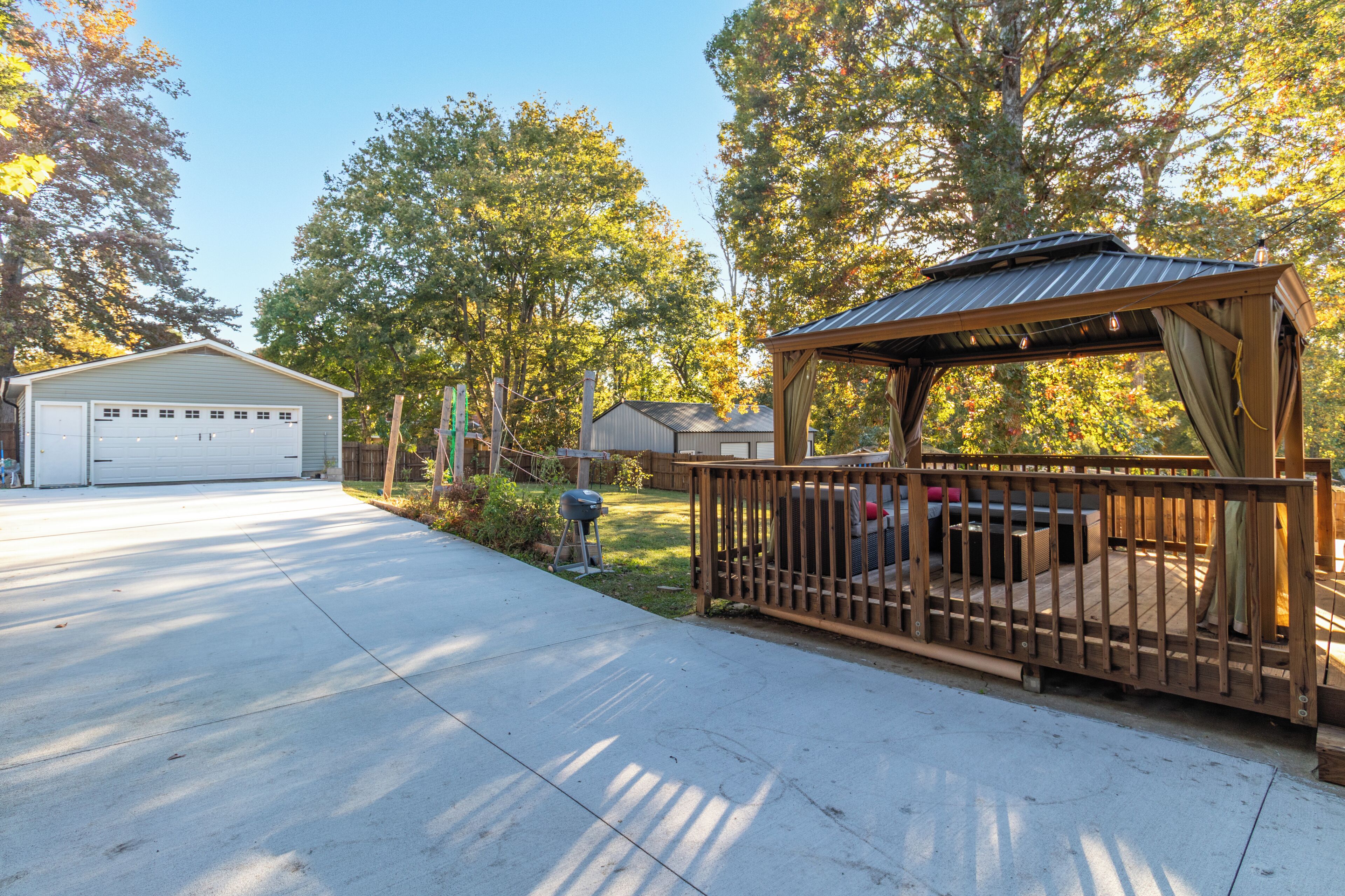 A residential property with a garage, a wooden deck, and a covered outdoor seating area.