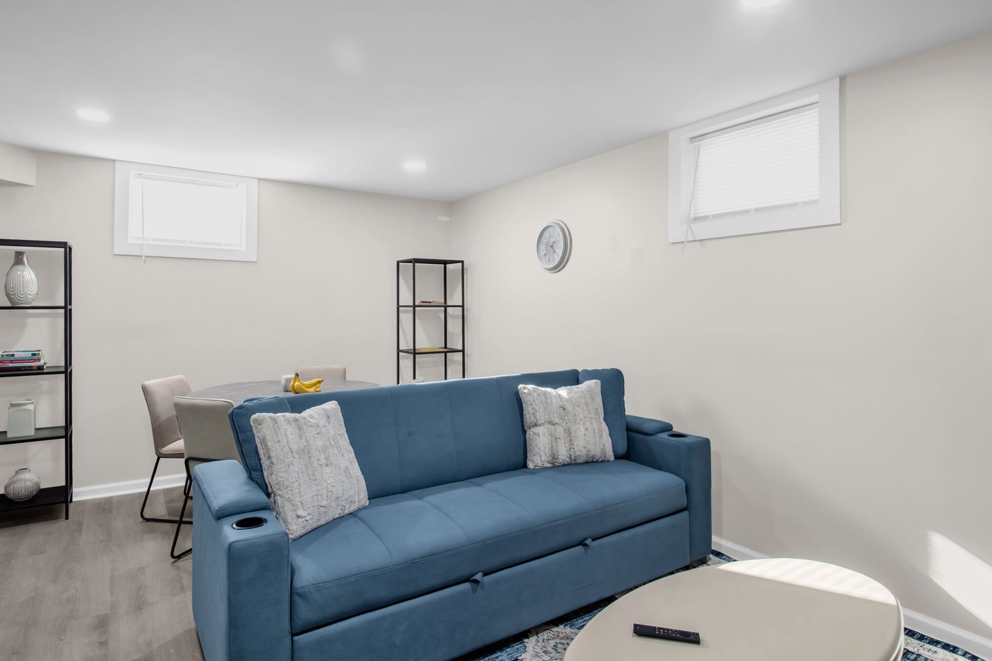 A modern living room with a blue sofa, a round coffee table, and a dining area with a table and chairs.