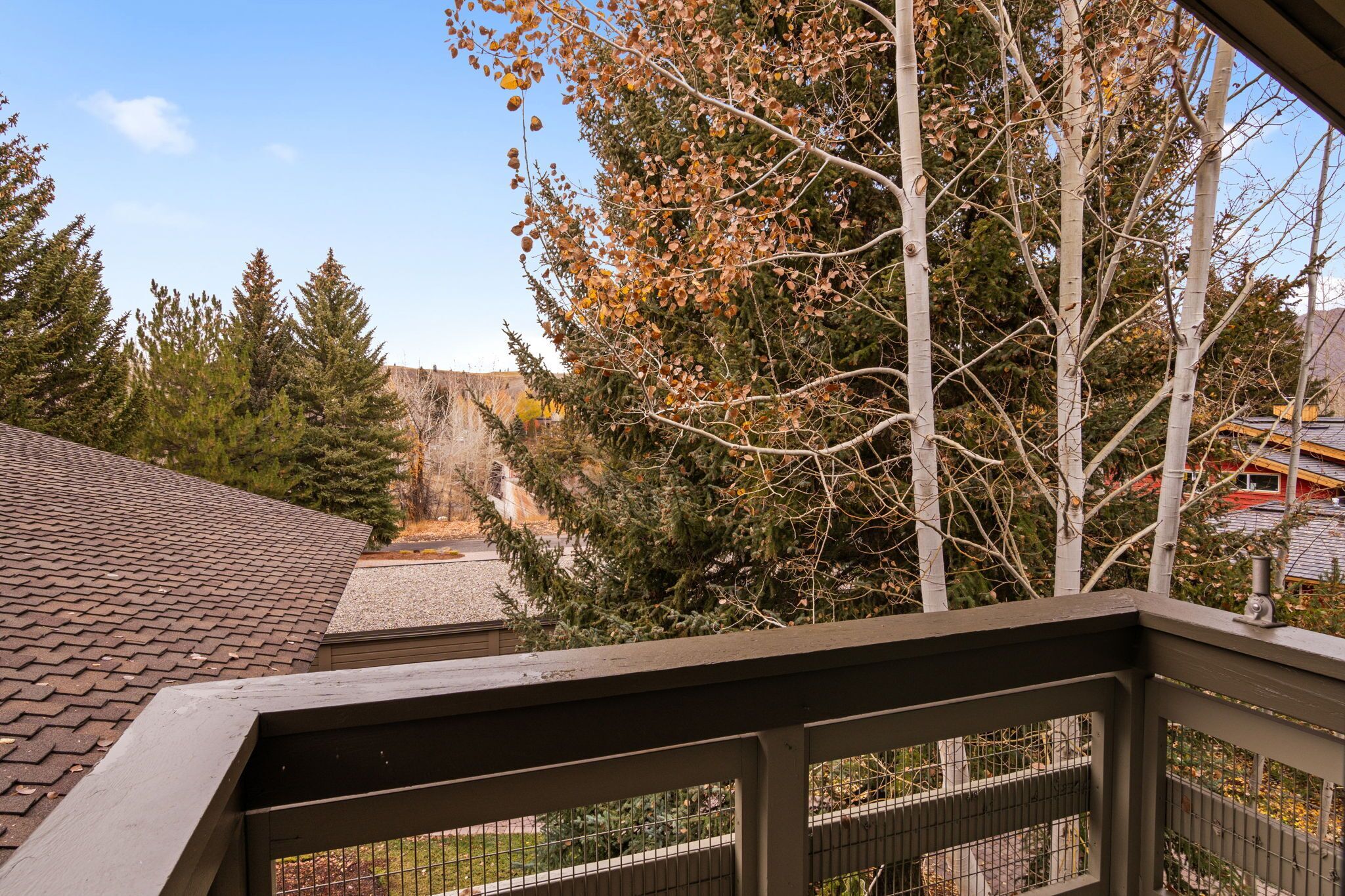 A view from a balcony overlooking a landscaped area with trees and a distant building.