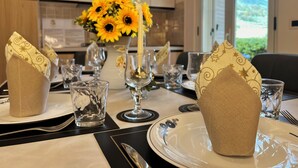Une table à manger dressée avec de la belle verrerie transparente, un vase rempli de tournesols et une bougie.