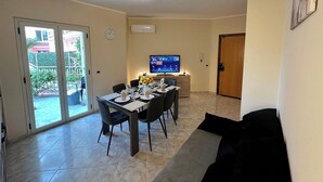 Un coin repas avec une table dressée pour quatre personnes, un téléviseur fixé au mur et une porte-fenêtre coulissante donnant sur une terrasse.