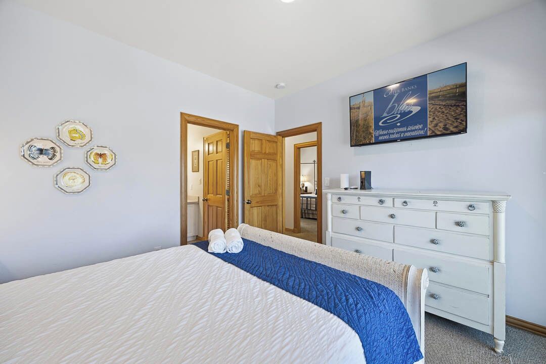 Une chambre d’hôtel avec un lit, une commode et un tableau au mur.