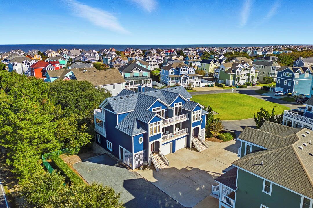 A residential area with a prominent blue house featuring a balcony and a garage.